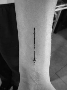 a black and white photo of a person's foot with an arrow tattoo on it