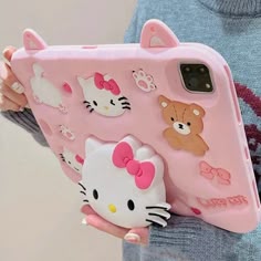 a woman holding a pink hello kitty phone case