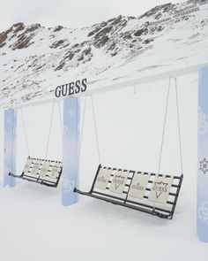 two swings in the snow that say guess and one with hearts on them, hanging from chains