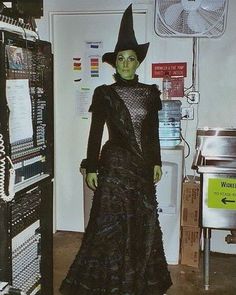 a woman in a witch costume standing next to a refrigerator