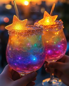 two glasses filled with liquid and stars on top of each glass, one holding a straw