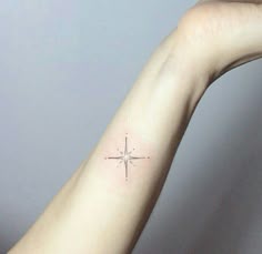 a person's arm with a small cross tattoo on the left side of their arm