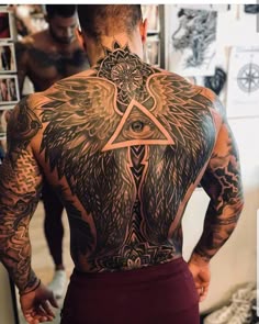 a man with tattoos on his back has an all seeing triangle and wings tattoo on his back