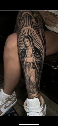 a woman's leg with a tattoo on it and an image of the virgin mary