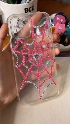 a person is holding a phone case with pink and silver stars on the front, while sitting at a desk