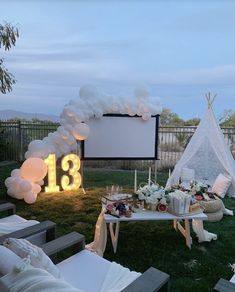 an outdoor movie party setup with balloons, candles and decorations on the grass near a teepee tent
