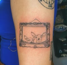 a woman's arm with a tattoo on it that has an image of two deer in a frame