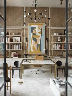 an office with lots of bookshelves and desks in front of a painting