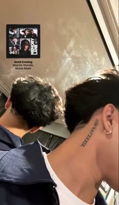 the back of a man's head with tattoos on his neck and behind him is an advertisement