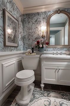 a white toilet sitting next to a sink in a bathroom under a large framed mirror