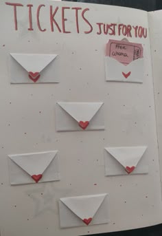 an open book with red hearts and white envelopes on the pages that say tickets just for you