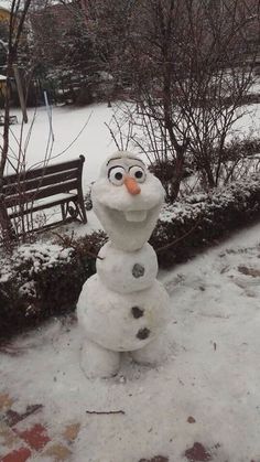 there is a snowman that has been made into a statue in front of a bench