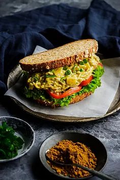 a sandwich with lettuce, tomato and other ingredients on a plate next to it