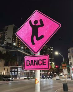 a pink sign that says dance on it in front of a city street at night