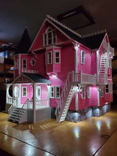 a pink doll house with stairs and lights