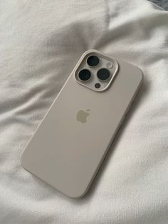 an iphone case sitting on top of a white bed covered in sheets and pillows,