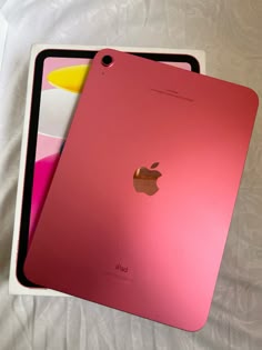 two apple ipads sitting next to each other on a bed