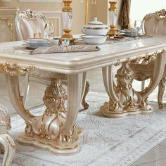 an ornate dining table with chairs and plates on it