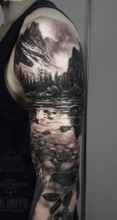 a man's arm with an image of mountains and trees on it
