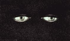 two blue eyes are seen in this black background, with the image of an individual's face visible