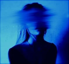 a blurry photo of a woman's face and hair in blue light,