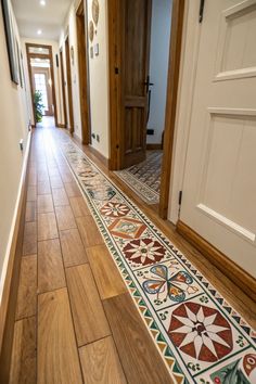 a long hallway with wooden floors and tile designs on the floor next to an open door