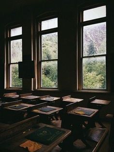 an empty classroom with desks and books in front of three large windows that look out onto the mountains