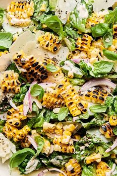 a salad with corn, spinach and cheese on it is ready to be eaten