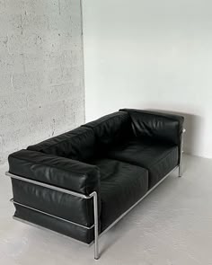 a black leather couch sitting on top of a white floor