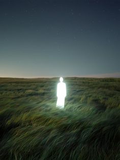 a person standing in the middle of a field at night