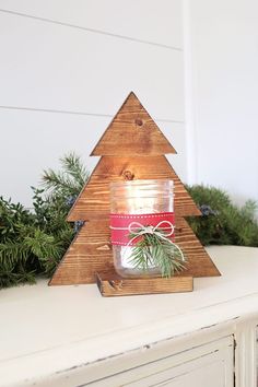 a wooden christmas tree candle holder on top of a mantle