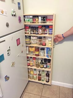 a refrigerator that has some food on the shelves next to it and someone reaching for something