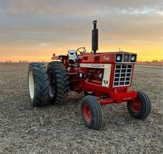a red tractor parked on top of a dry grass field
