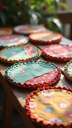 many colorful plates on a wooden table with plants in the backgroung behind them