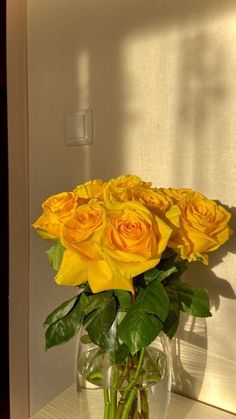 a vase filled with yellow roses on top of a table