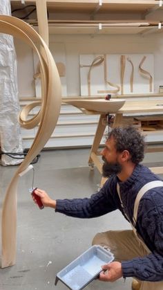 a man is working on a sculpture in a shop with woodworking tools and plywood