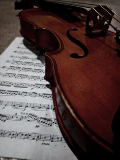 an old violin sitting on top of sheet music