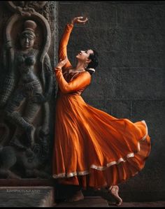 a woman in an orange dress is dancing