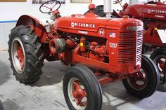 an old red tractor parked in a garage