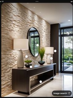 a modern console table with two lamps and a large mirror on the wall behind it