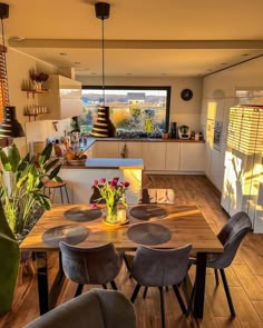 a dining room table with chairs around it in front of an open kitchen and living area