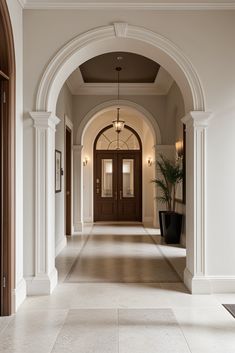 an arched hallway leading to two doors and a potted plant on the floor in front of it
