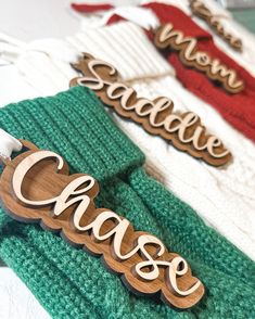 three wooden name plaques sitting on top of green sweaters with red and white striped ties