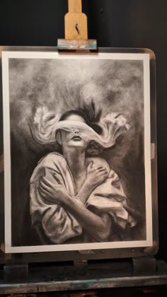 a black and white drawing of a woman with her hair blowing in the wind on an easel