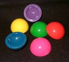 six plastic balls with different colors on a black surface