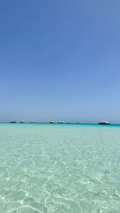 clear blue water with small boats in the distance