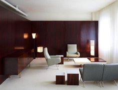 a living room filled with lots of furniture and walls covered in wood paneled panels