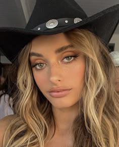 a woman wearing a black cowboy hat with buttons on the brim and long blonde hair