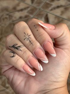 a woman's hand with pink and white nails holding up a small tattoo on her finger