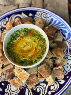 a blue and white plate topped with bread cubes and a bowl of hummus